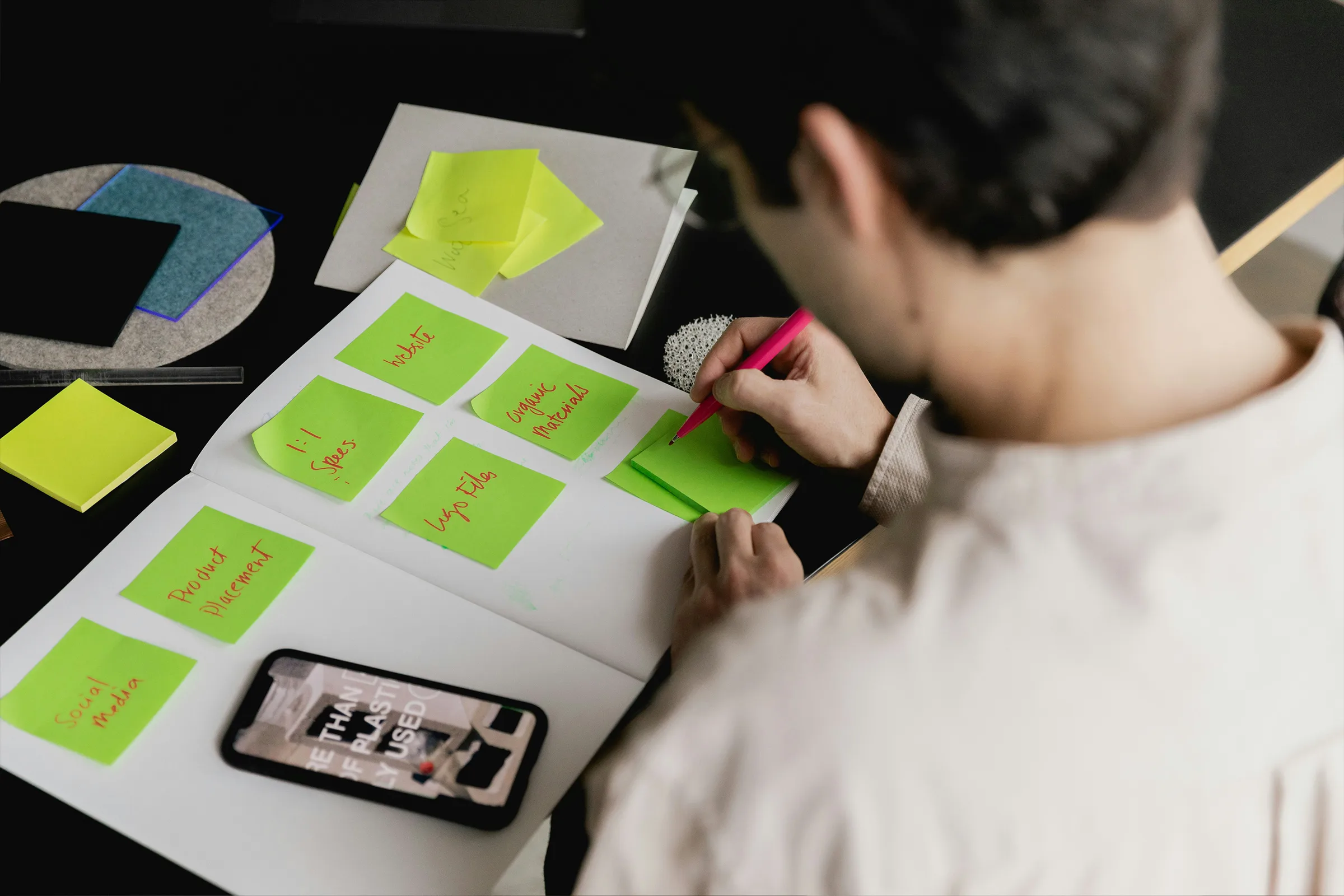 man writing on green note cards
